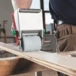 Adhesive roller applying glue to a wooden board